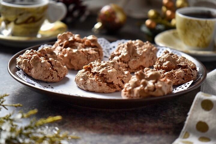 A tray of brutti ma buoni cookies on a table surrounded by Christmas decor.