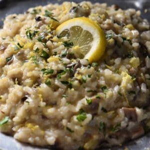 Creamy risotto topped with parsley and a lemon slice.