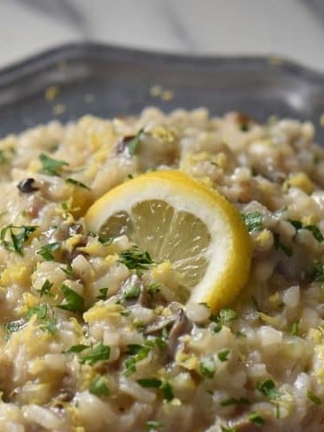 A close up of creamy risotto in a pewter plate.