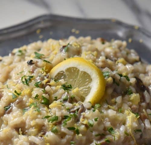 A close up of creamy risotto in a pewter plate.