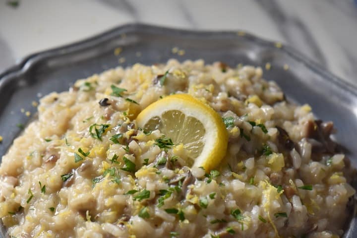 A close up of creamy risotto in a pewter plate.