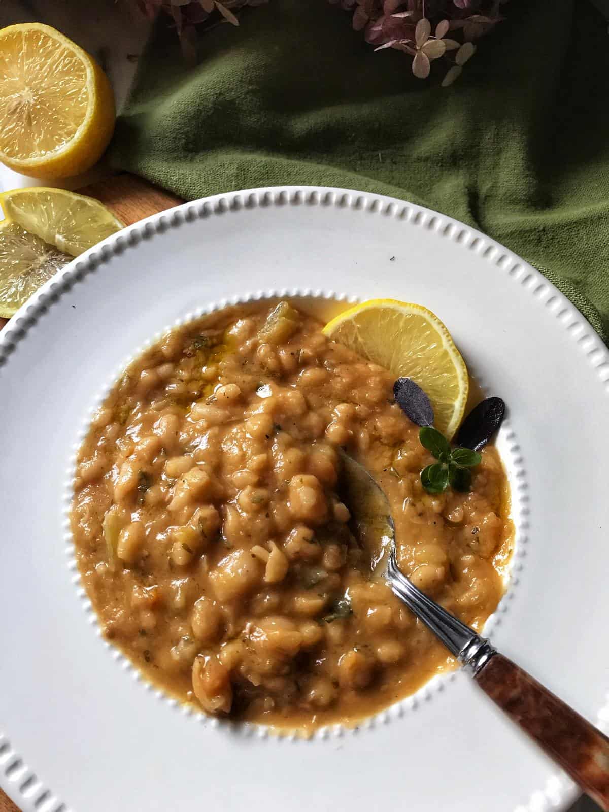 An overhead shot of a large bowl of White Bean Soup with a spoon on the side.