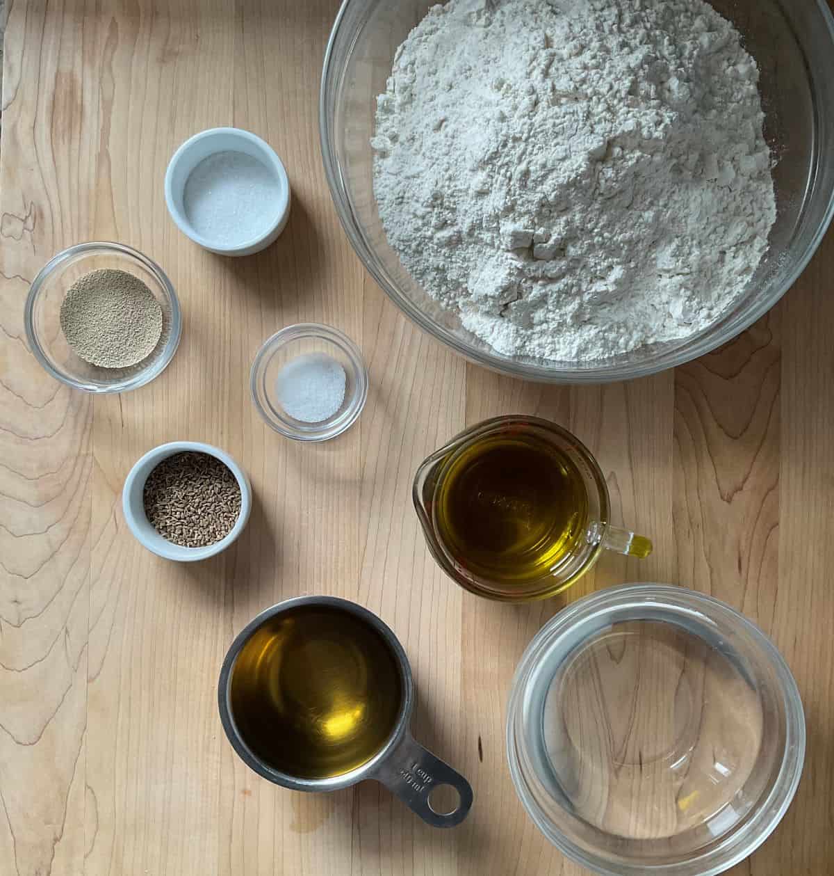 Ingredients to make Italian taralli on a wooden board.