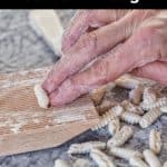 Cavatelli being shaped on a wooden grooved board.