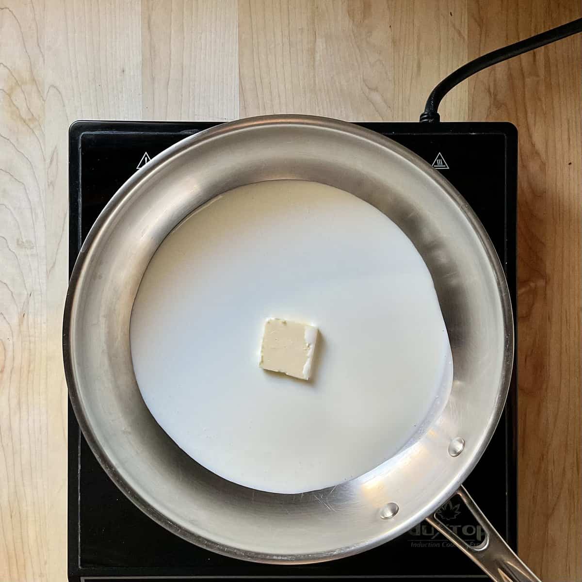 Whipping cream and butter being heated in a small pan.