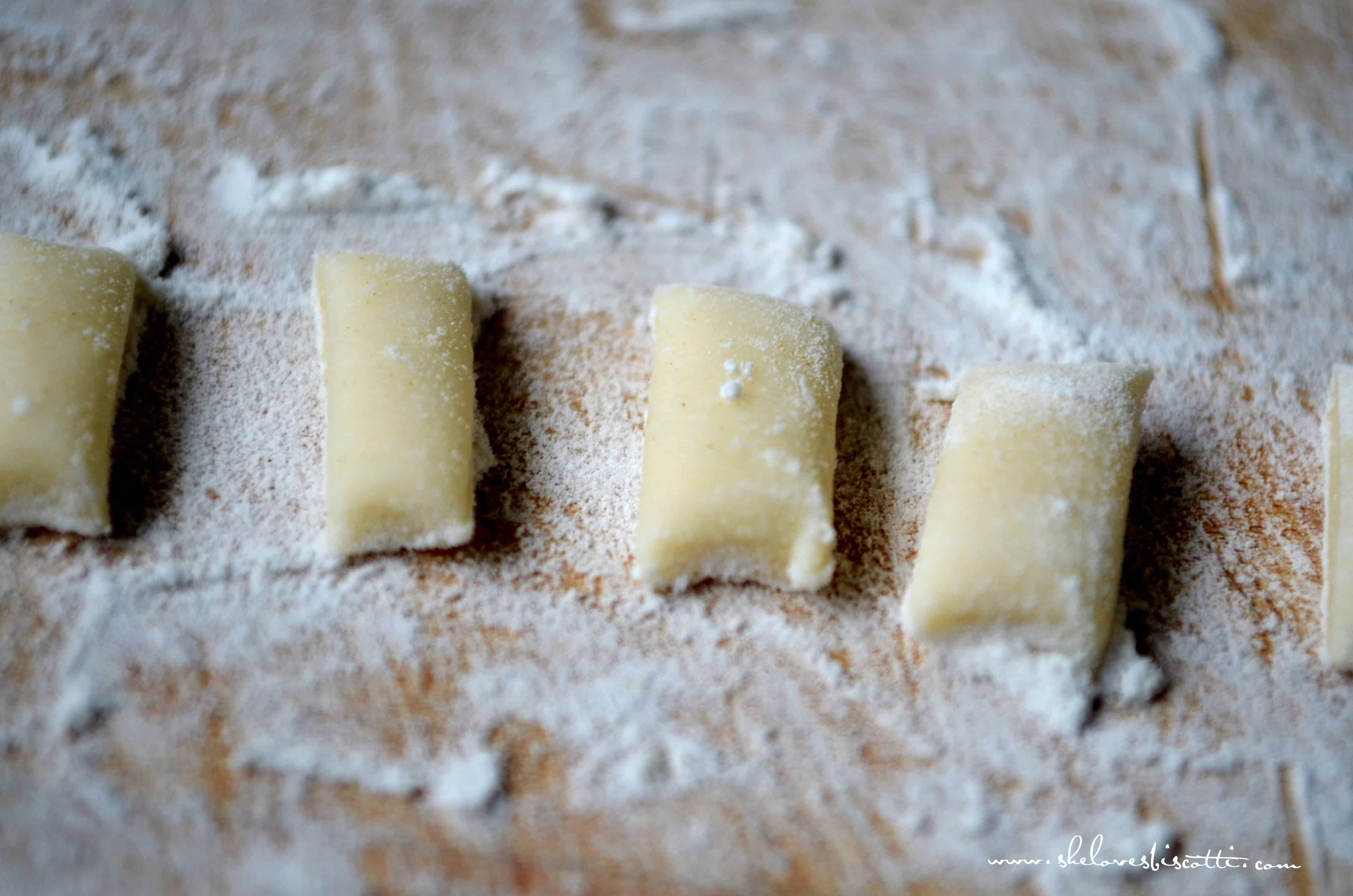 Cut up pieces of cavatelli dough on a floured wooden board. 