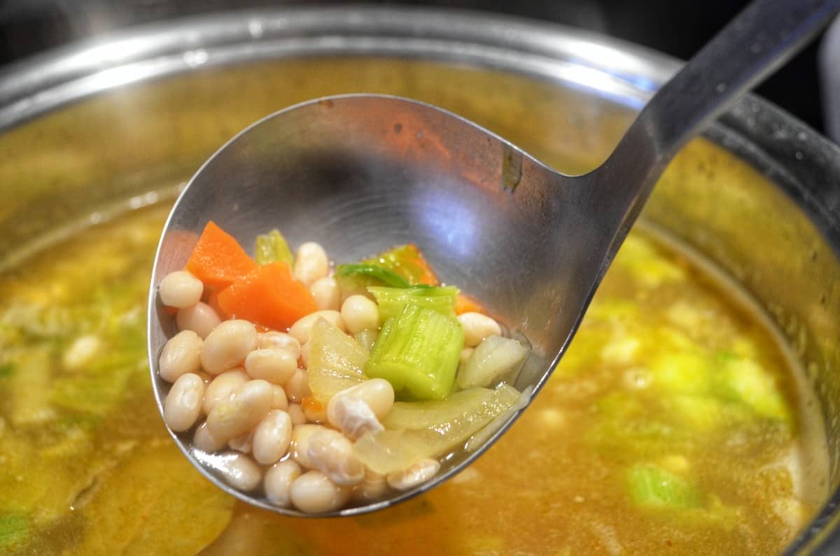 A close shot up of a ladle of the white bean soup.