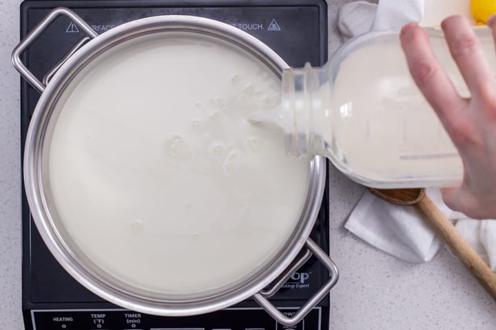 Whole milk being poured in a large pot in order to make ricotta cheese.