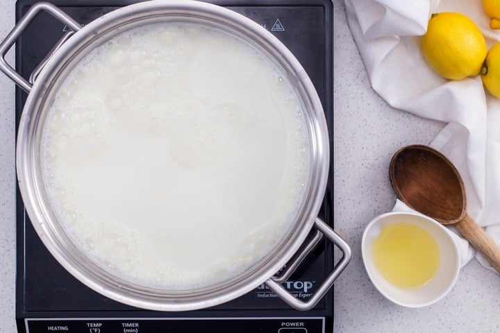 Whole milk is in the process of being heated before the other 2 ingredients are added to make ricotta cheese. 