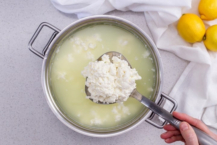 An overhead shot of a ladle of ricotta cheese.