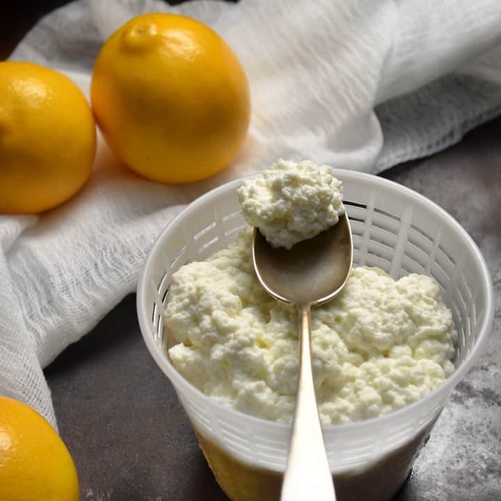 A spoonful of freshly made homemade ricotta cheese over a cheese basket.