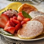 Lemon Ricotta Pancakes in a white plate next to macerated strawberries.