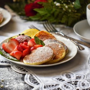 Lemon Ricotta Pancakes, lightly dusted with icing sugar, on a white plate.