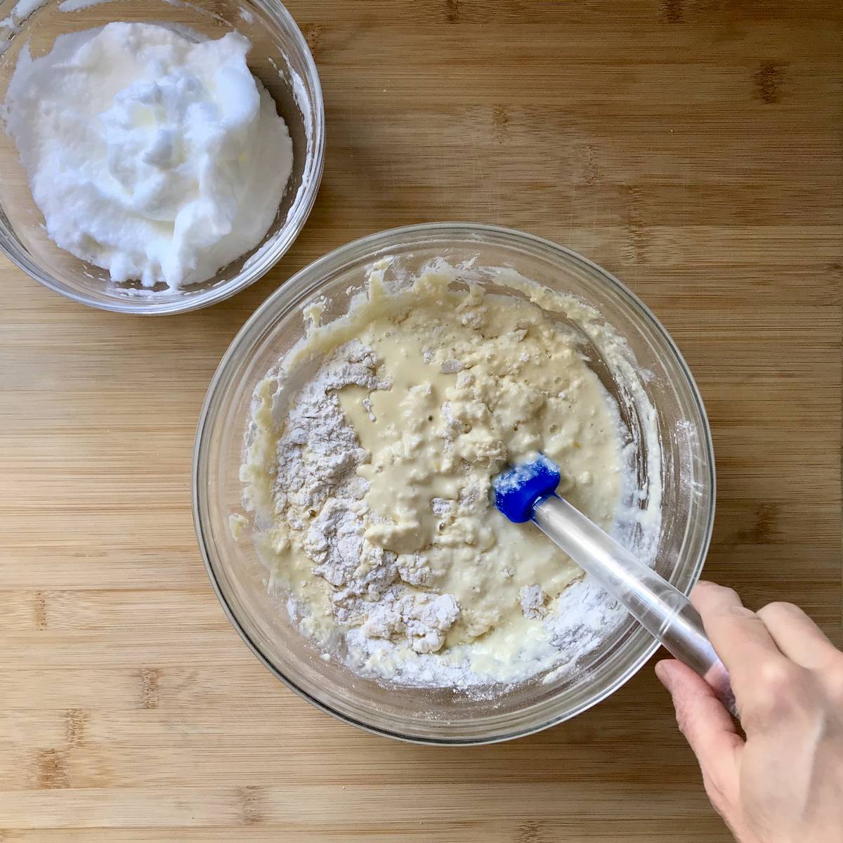 Stiff egg whites in a bowl next to the combined pancake batter.