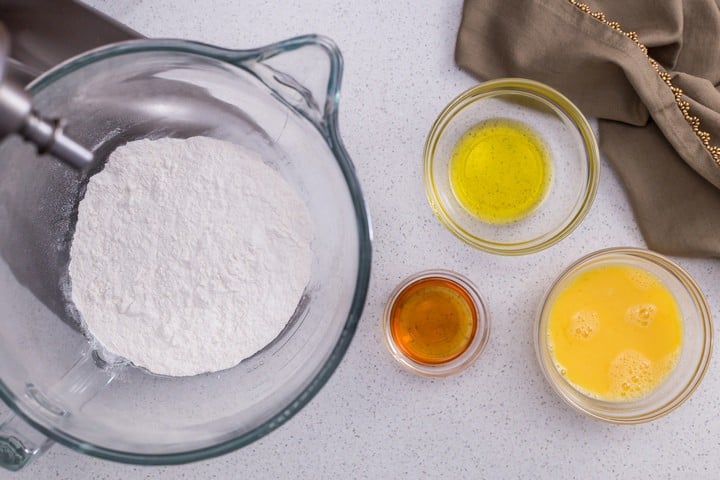 An overhead shot of some of the ingredients need to make this Italian cookie recipe called Crostoli. Seen in the photo are dry ingredients, eggs, oil and liquor.