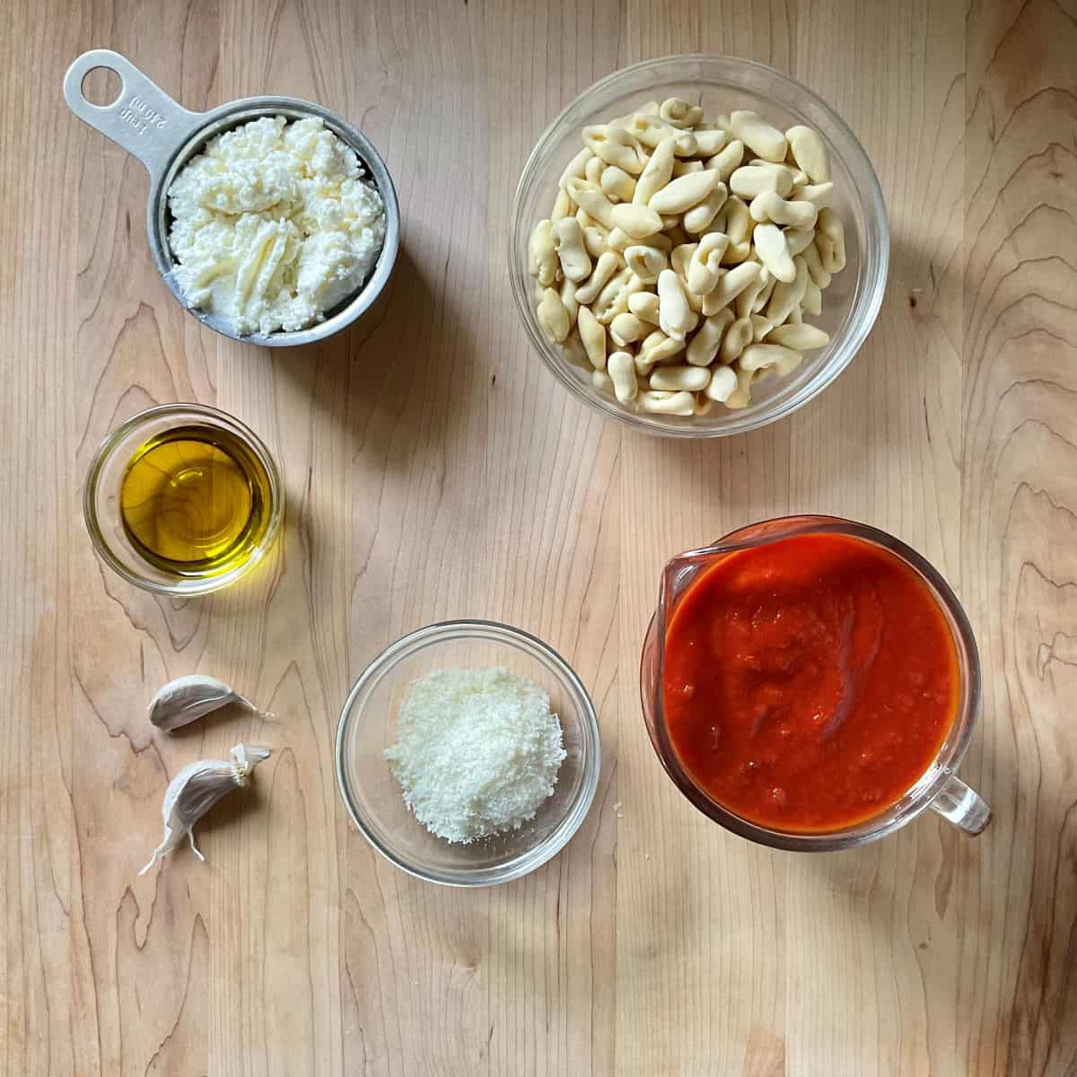 Ingredients to make ricotta tomato sauce with cavatelli on a wooden board. 