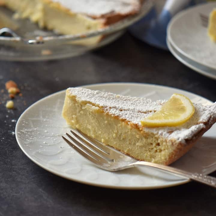 A slice of old fashioned Italian pie made with ricotta, on a white plate, dusted with icing sugar.