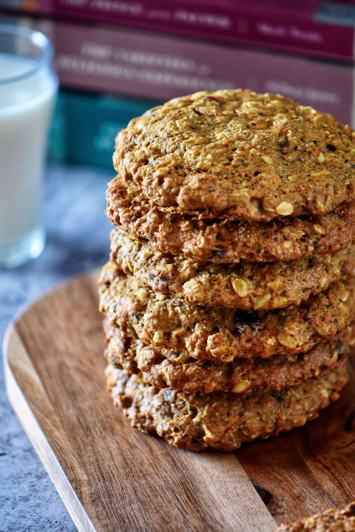 A stack of giant carrot cookies on a wooden board.