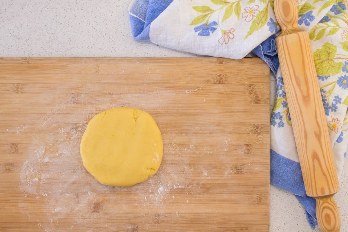 The dough to make the pie crust for the Easter pie is on a wooden board, ready to be rolled out.