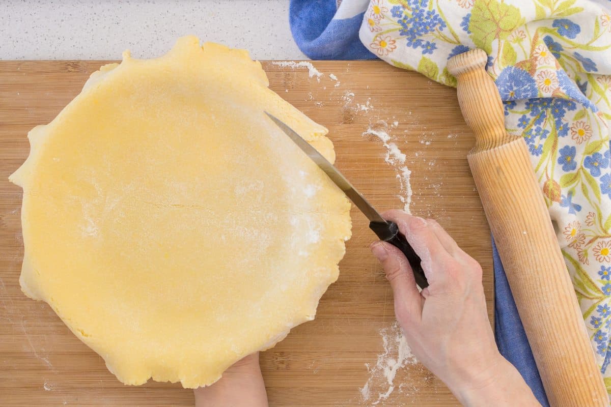 A knife is used to trim the excess pie dough of this Italian pie.