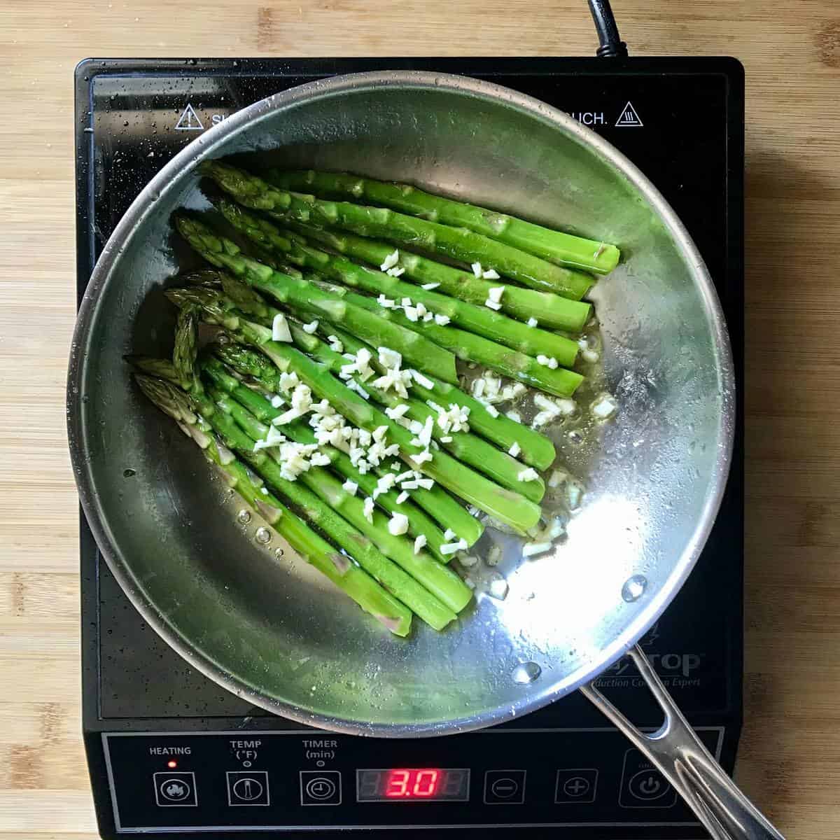 Sauteed asparagus with chopped garlic in a pan.