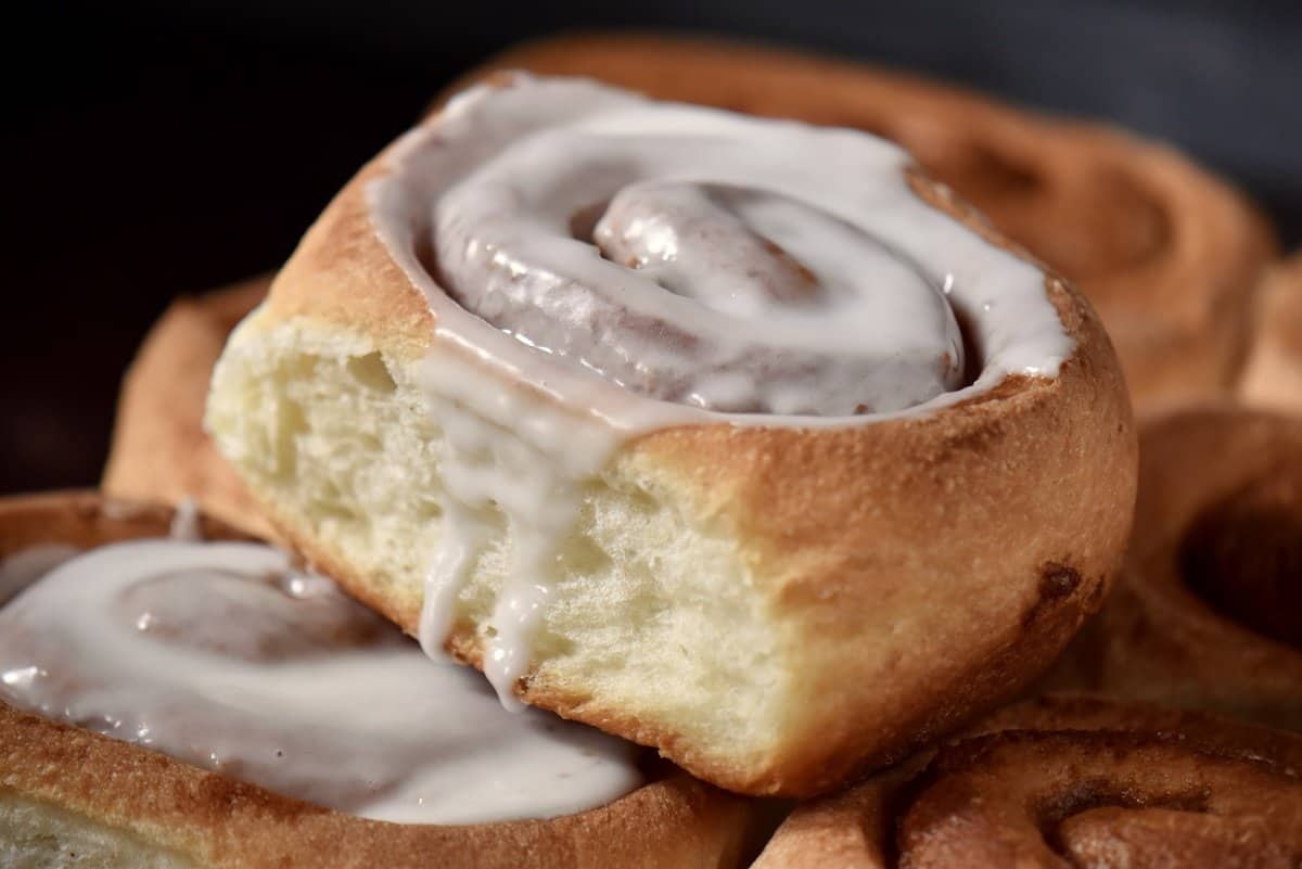 A close up photo of a cinnamon roll with vanilla icing.