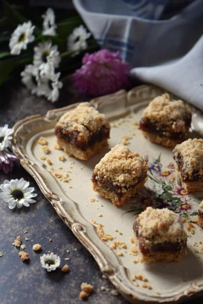 Date squares in a tray, surrounded by white daisies.