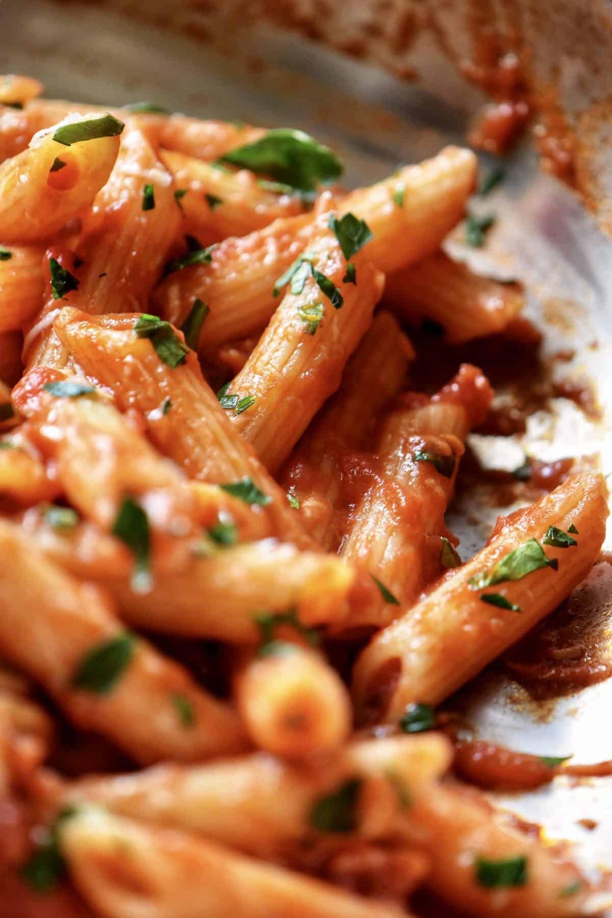 Spicy Penne all'Arrabbiata in a pan garnished with chopped parsley.