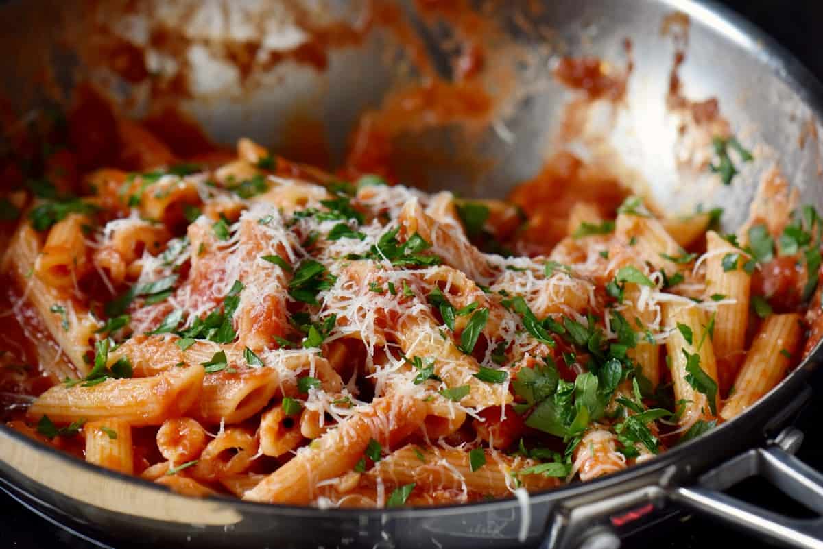 An Italian pasta recipe with Arrabbiata sauce garnished with grated cheese and parsley.