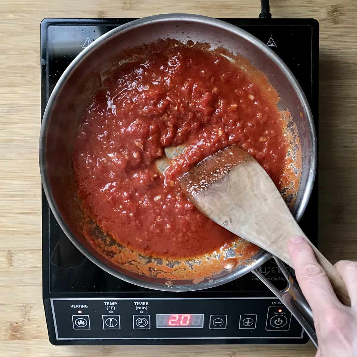 Canned tomatoes simmering in a saucepan.