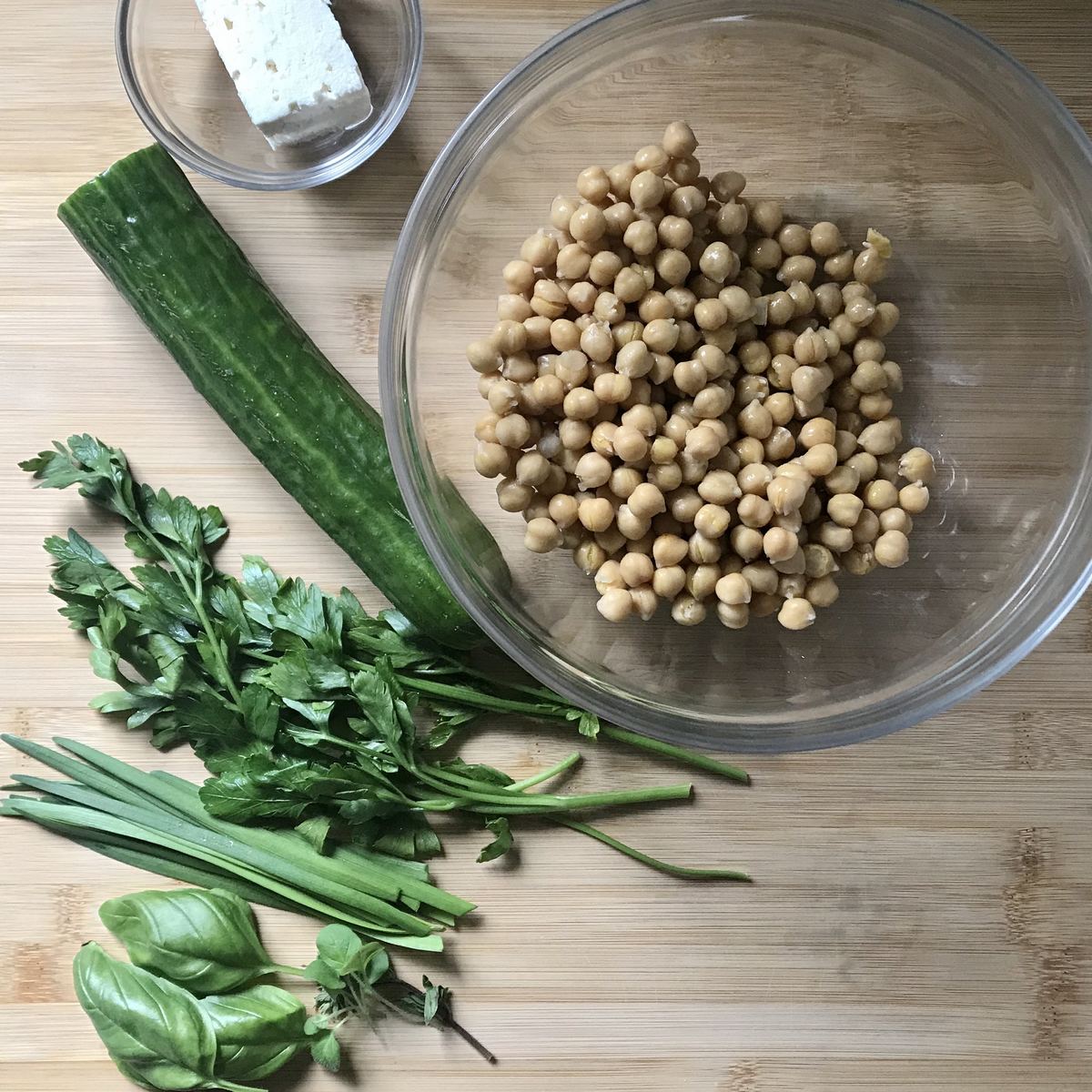 Fresh herbs next to a bowl of chickpeas.