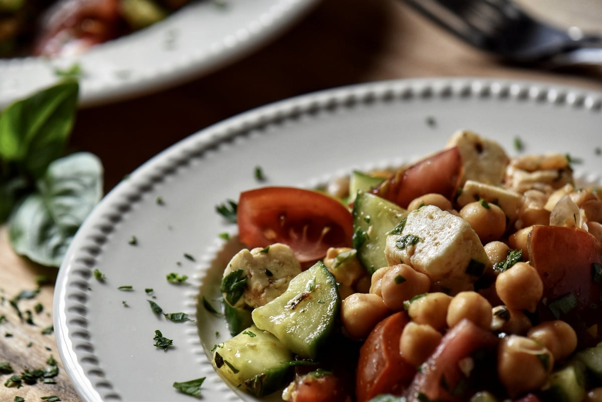 Chickpea salad in a white dish garnished with fresh parsley.