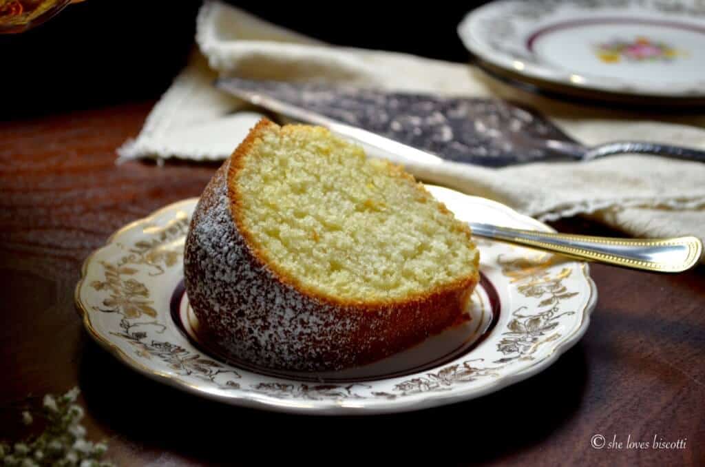 A slice of an Italian lemon cake called ciambella on a cake plate.