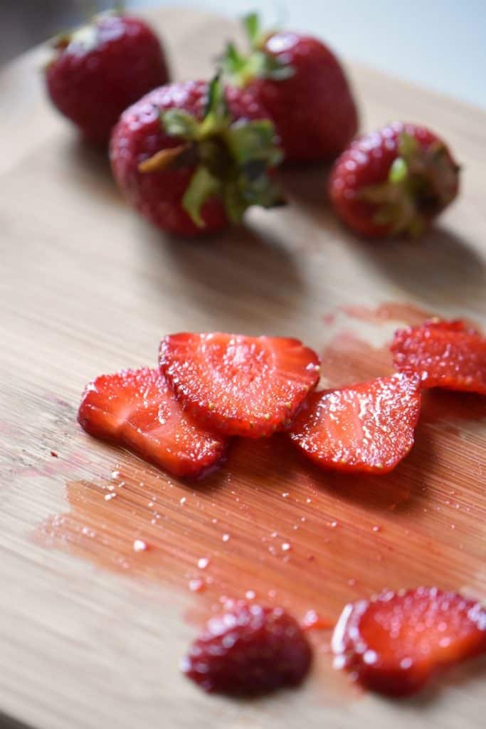 Sliced strawberries on a wooden board.