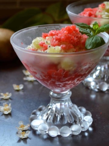 Kiwi granita in a bowl surrounded by kiwi flowers.