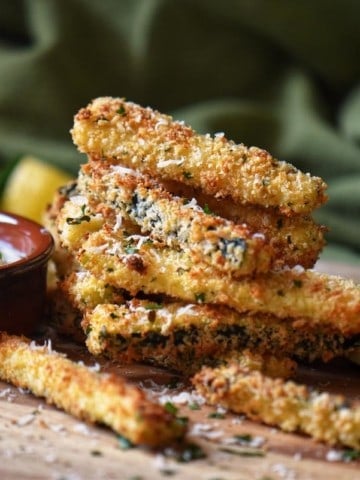 Herb encrusted zucchini on a wooden board.