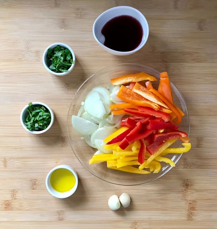 The ingredients to make Peperonata on a wooden board.