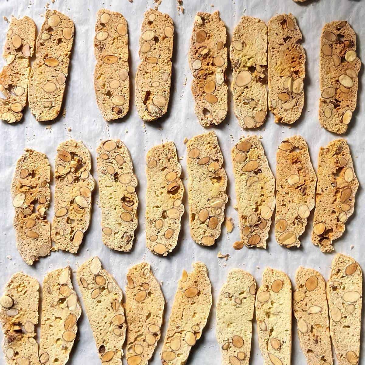 Thin sliced biscotti on a parchment lined baking sheet.