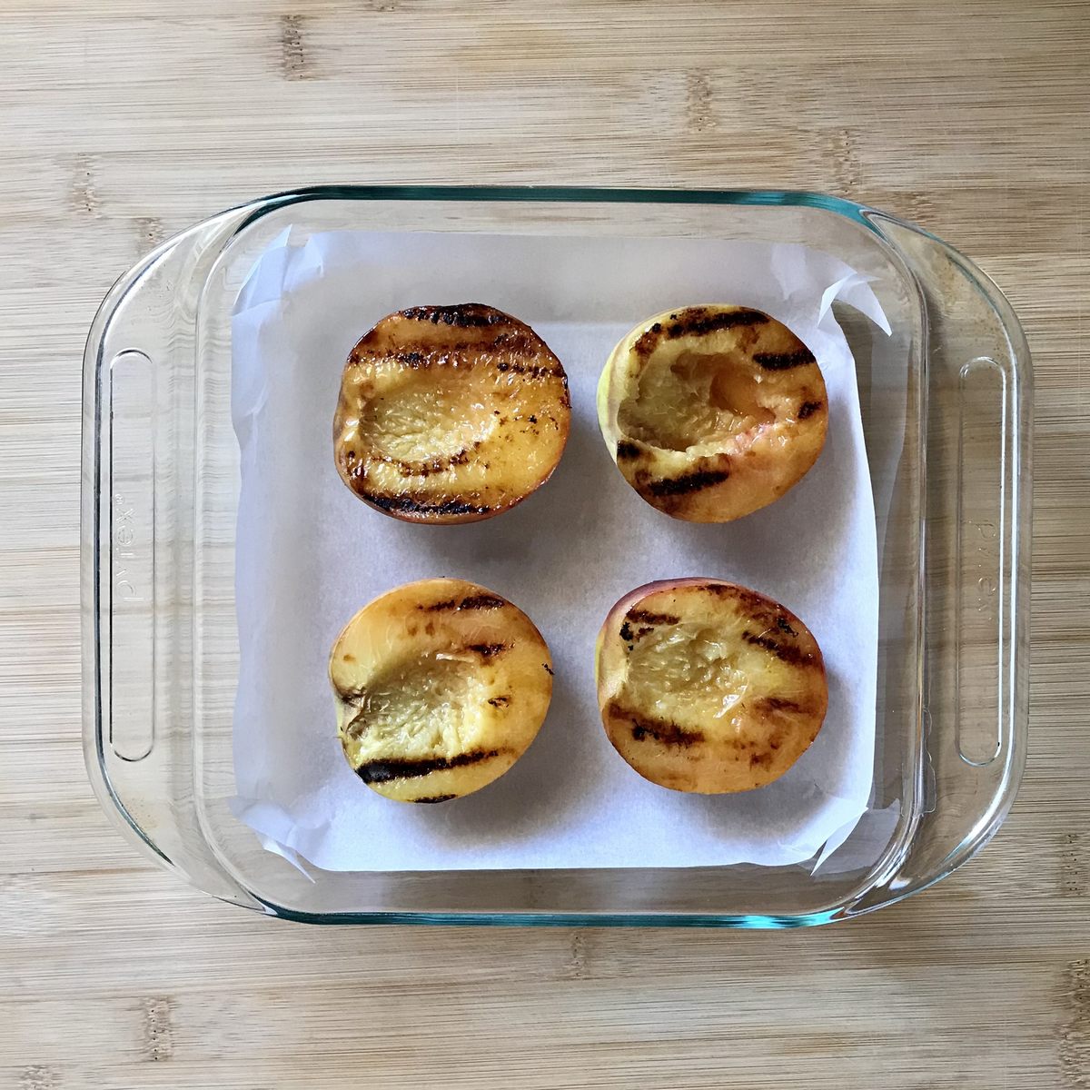 Grilled peaches in a baking dish.