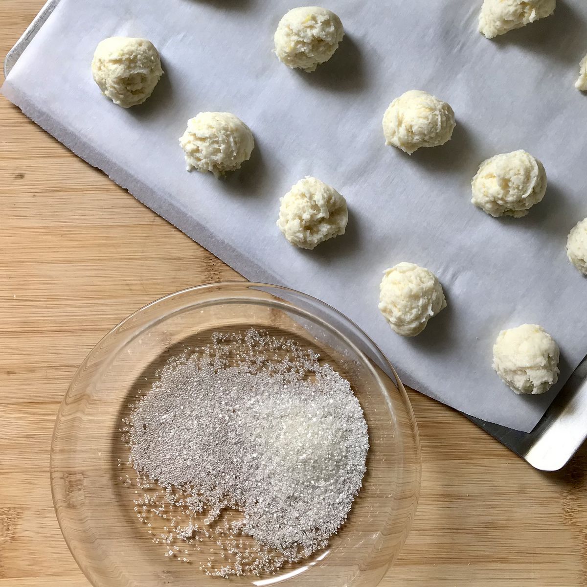 Ricotta cookies with sanding sugar on a cookie sheet.