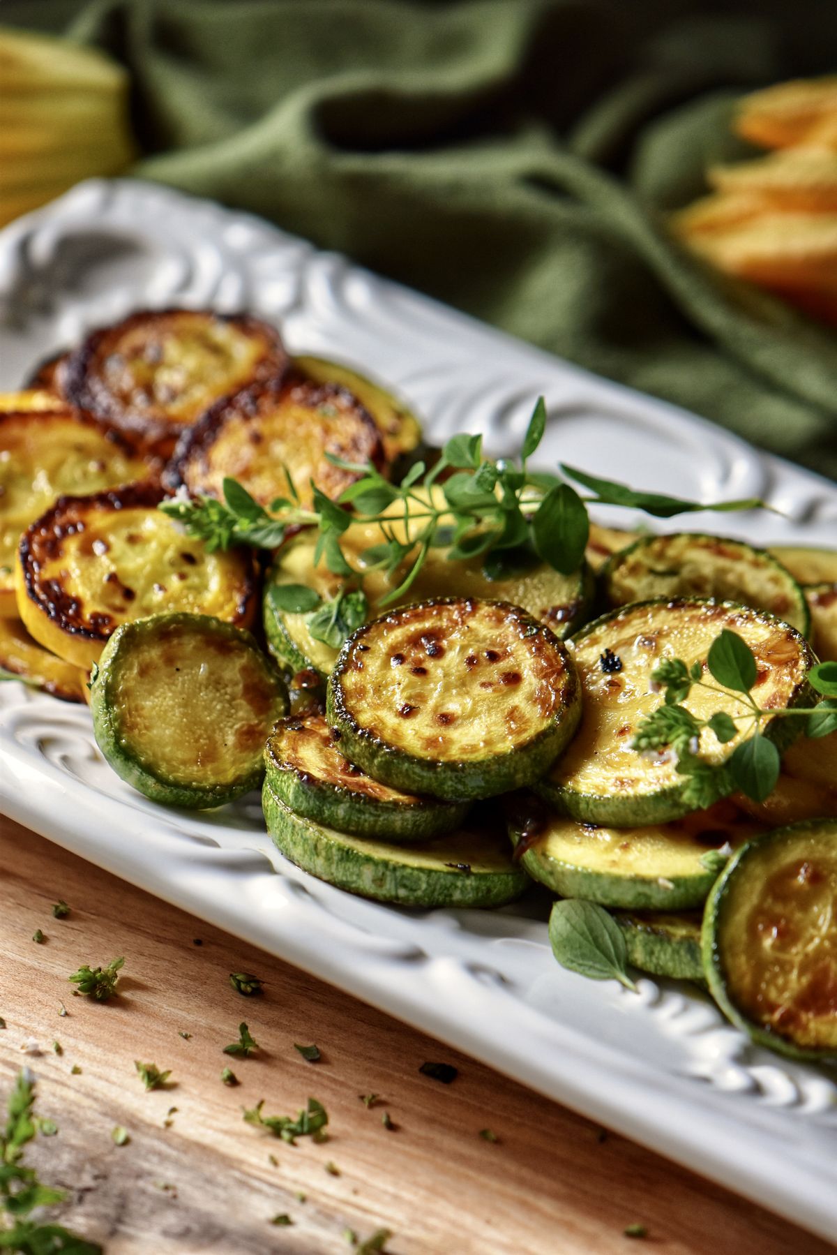 Italian sauteed zucchini on a white dish garnished with fresh oregano.