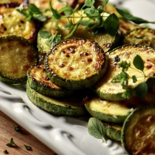 Yellow and green Italian Zucchini on a white serving tray.