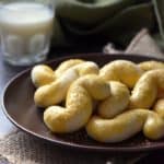 A few S cookies on a plate with a glass of milk in the background.