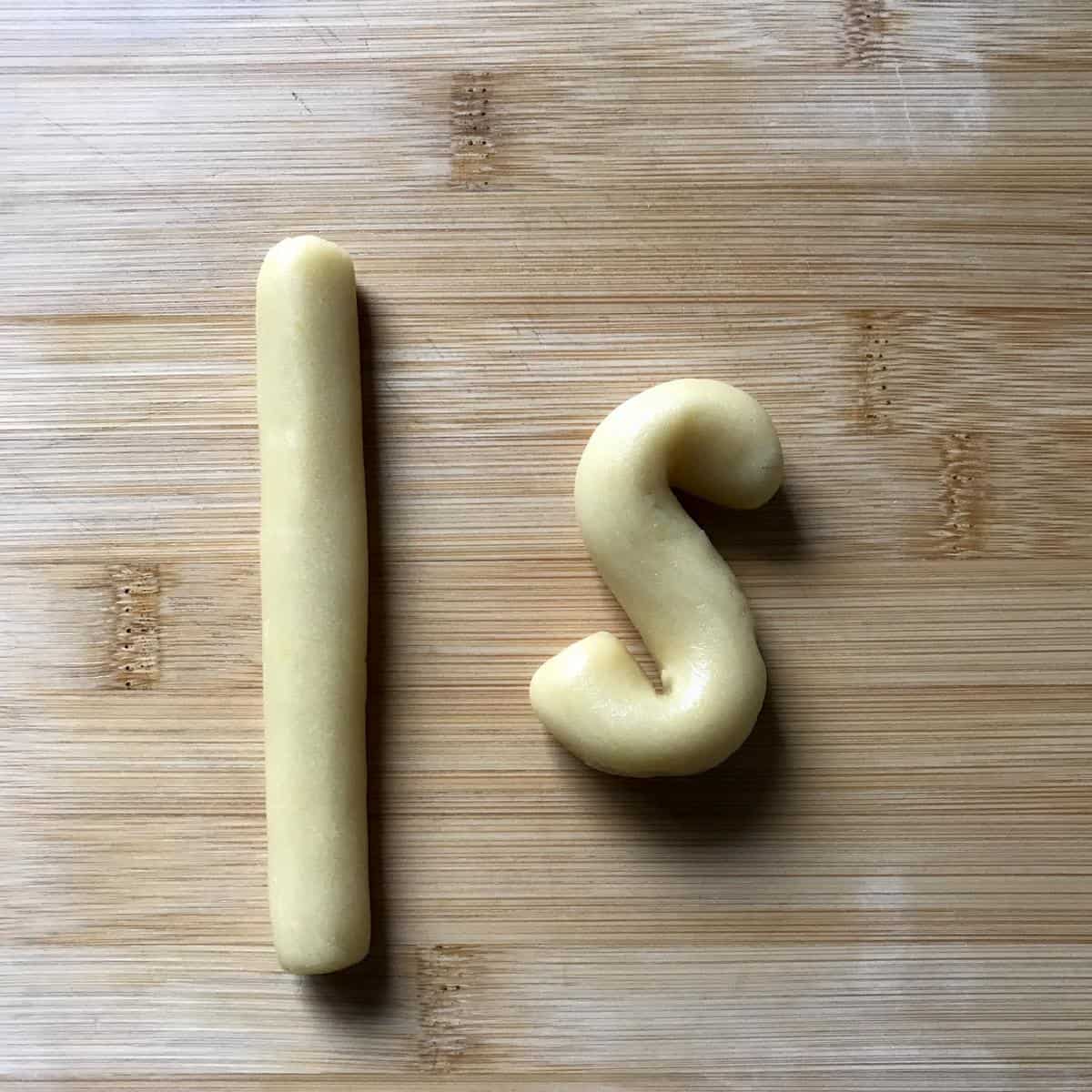 The cookie dough rolled into a log, next to a formed S cookie.