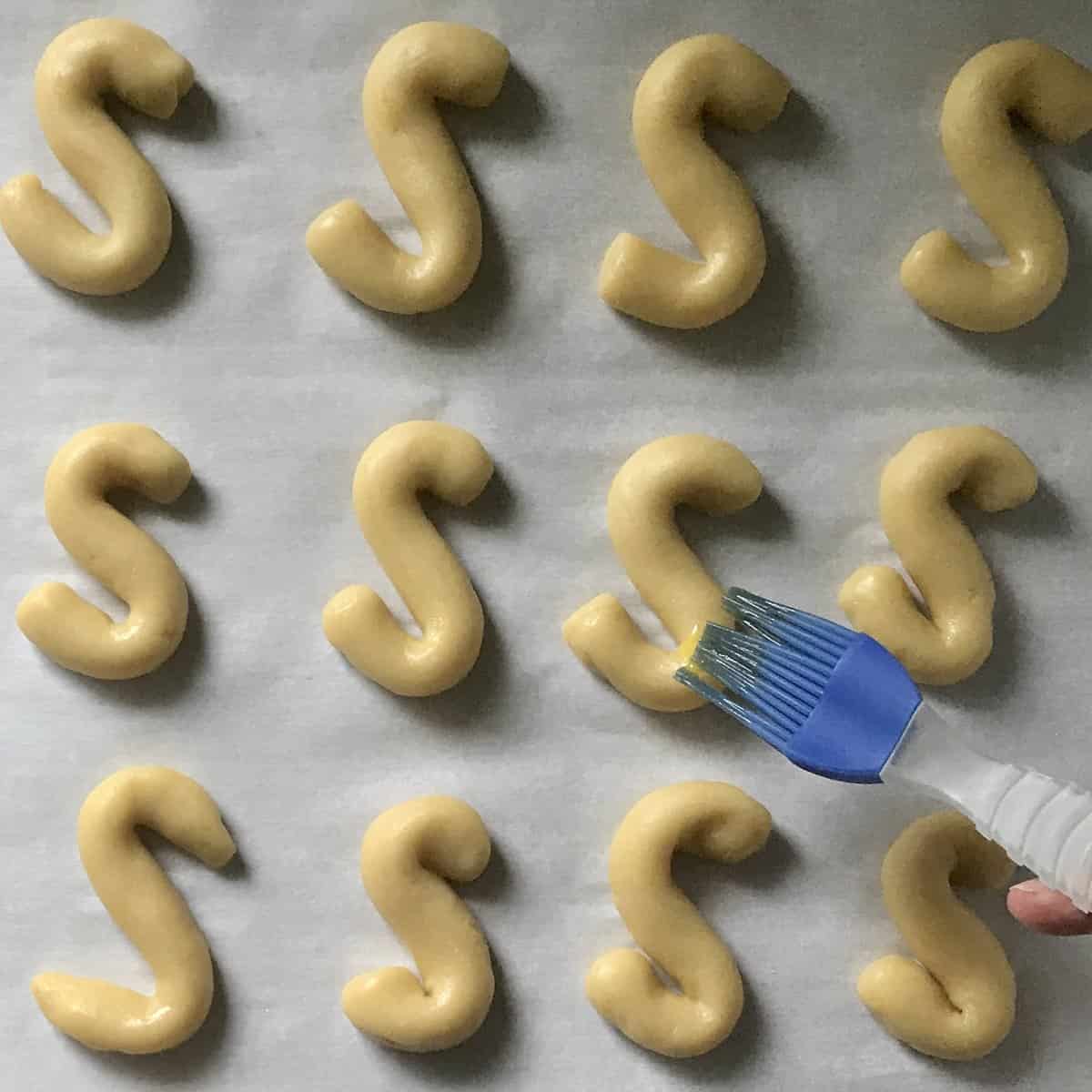 Egg wash being brushed on cookies.