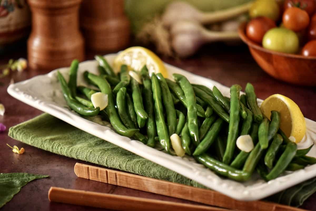 Steamed string beans with garlic on a white dish.