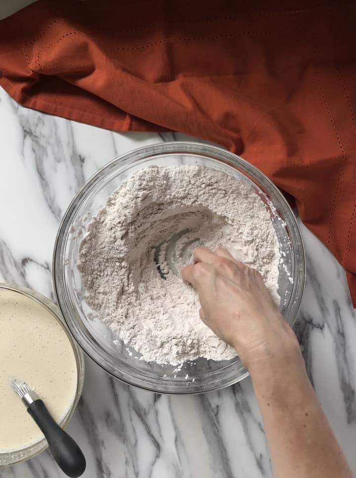 A well is being created in the bowl with the dry ingredients.