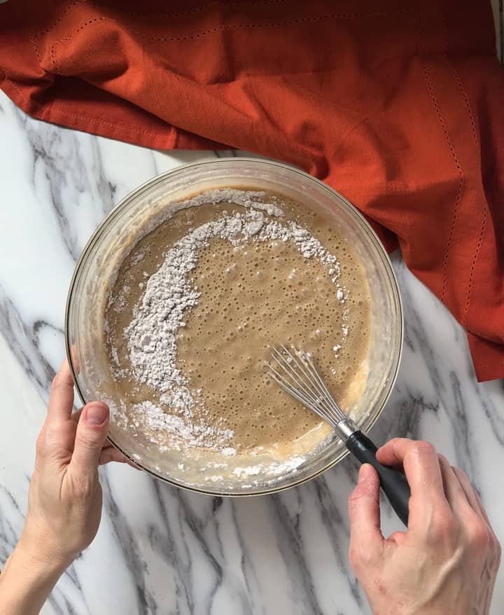 The wet and dry ingredients for the honey cake are being whisked together.