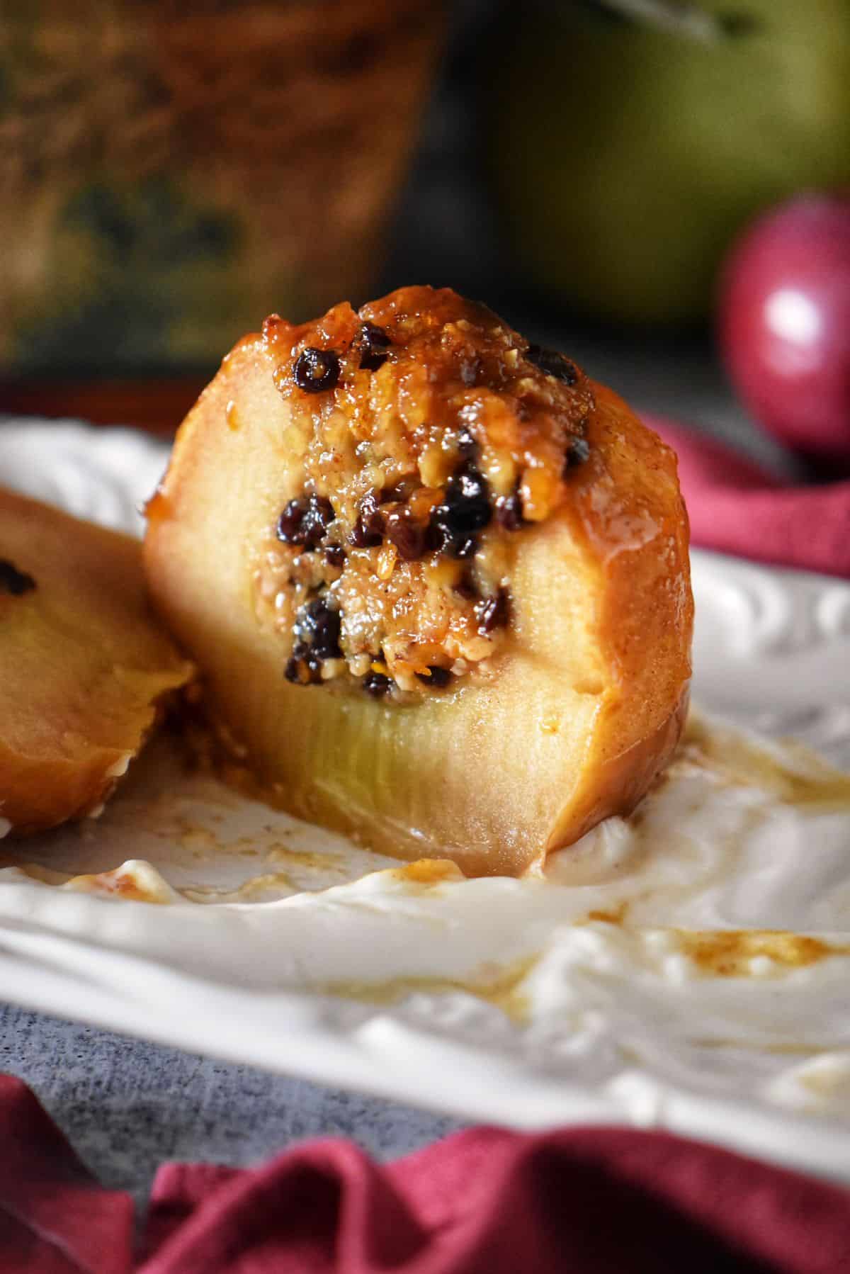 Sliced baked apple with caramelized top showing the warm, spiced oat and currant filling inside.