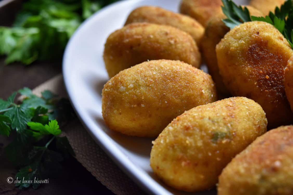 Croquettes are seen on a white serving platter.